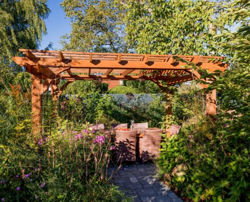 Sitzecke in einem blühenden Garten, Pergola aus Holz