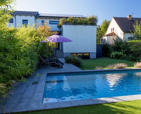 Pool mit einer Natursteinterrasse, ein Sonnenschrim im Hintergrund