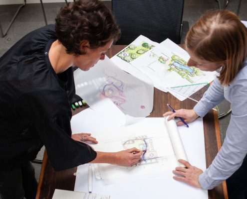 Zwei Frauen bei der Gartenplanung, Zeichnungen auf dem Tisch