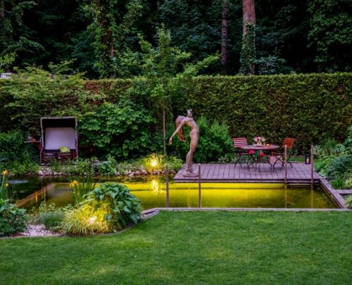 Schwimmteich im Garten beleuchtet am Abend